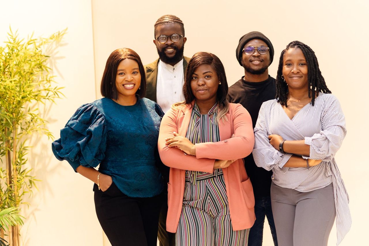 A smiling team of five colleagues in a Lagos office