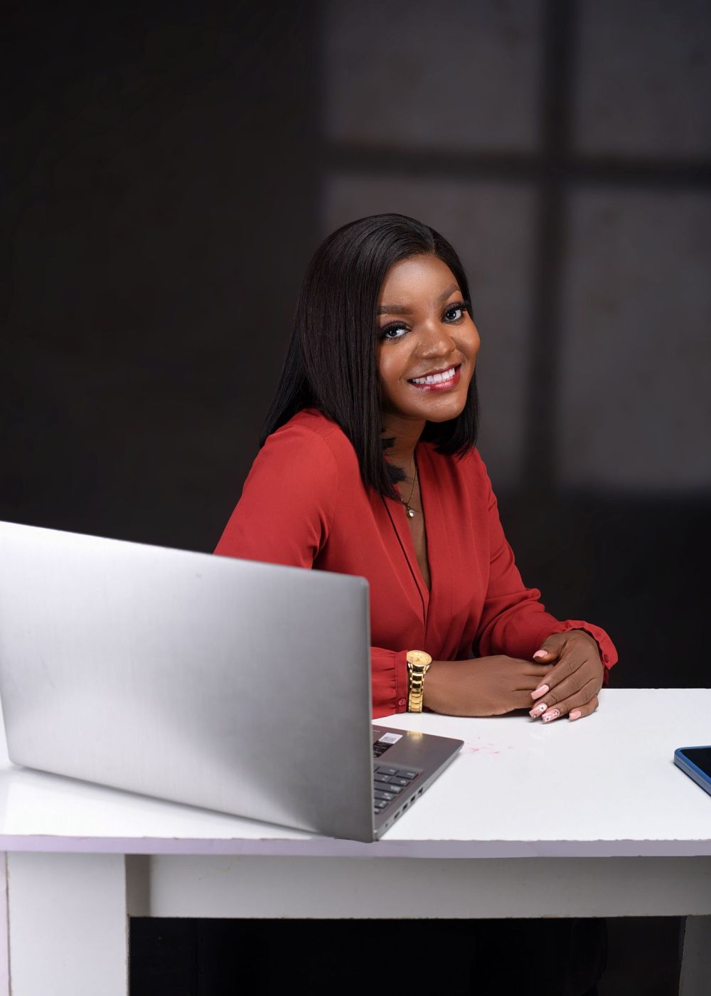 A professional smiling at her desk with a laptop
